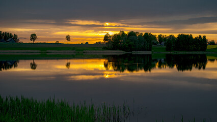 Obraz premium beautiful sunset, sunrise landscape by the lake, reflections on the surface of the calm lake water, bright colors,