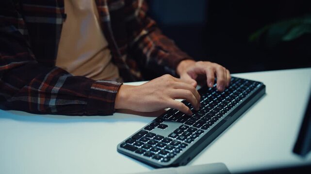 Close up young Male programmer hands typing on keyboard in dark home office at night. AI technology, cybersecurity, software developer, freelance innovation, database system, digital network concept.