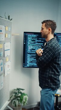 Vertical Screen : Young Caucasian male programmer write creative plan on whiteboard and coding on computer in home office. AI technology, cybersecurity network, agile strategy, business innovation.