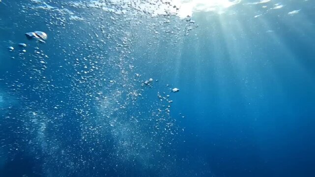 Underwater scene with a stream of rising air bubbles and sun rays penetrating the deep blue ocean water creating a serene and dynamic aquatic environment Keywords: underwater, water, bubbles, air