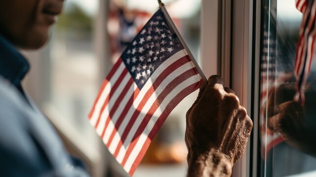 A mature person holding a small american flag against a window pane representing patriotism national pride and a deep connection to civic identity