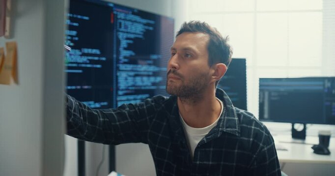 Young Caucasian male programmer write creative plan on whiteboard and coding on computer in home office workspace. AI technology, cybersecurity network, agile strategy, business innovation concept.