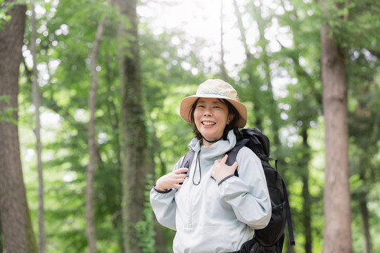新緑の森で趣味で登山やトレッキングが楽しい笑顔のアクティブな女性 初夏のアウトドアのお出かけイメージ　カメラ目線