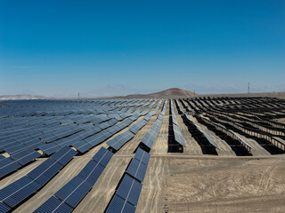 Fototapeta premium Huge photovoltaic solar park with aligned panels in a desert area