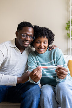 Happy couple holding positive pregnancy test at home