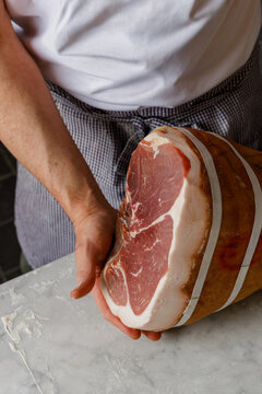 Pizzaiola in a pizzaria demonstrates quality jamon before slicing
