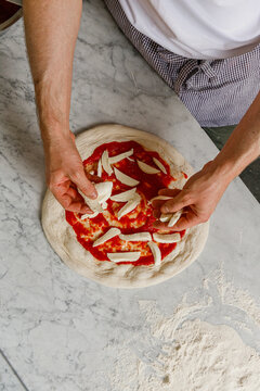 A pizza chef puts cheese on a pizza for further baking.