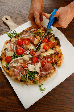 Pizza maker cuts pizza with scissors. Professional pizzeria kitchen