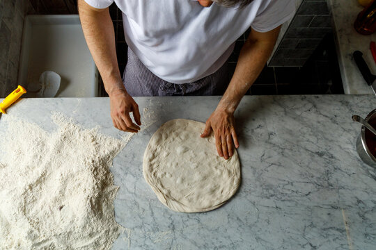 Pizza maker kneads dough and shapes pizza pan