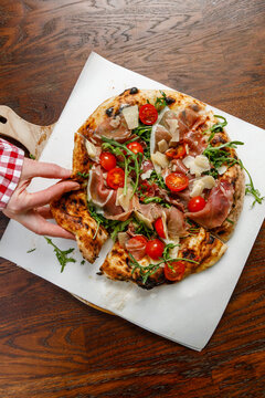Girl taking a slice from a large pizza isolated