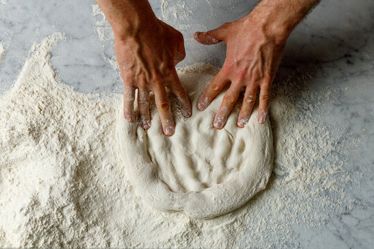 Pizza maker kneads dough and shapes pizza pan