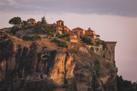 Meteora monastery perched on a rock cliff at sunset