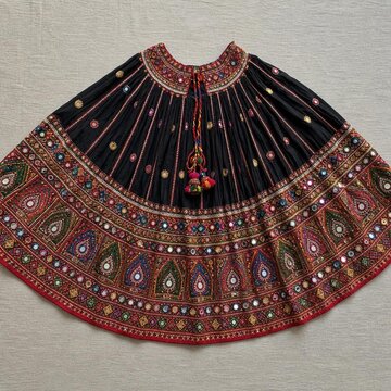 Top-down view of a chaniya skirt with embroidered mirrors and colorful threads.