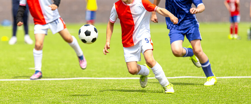 Youth Soccer Action Shot: Close-Up of Kids Running and Dribbling Ball on Green Pitch
