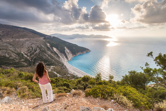 Woman enjoying the sunset over famous Myrtos beach, Kefalonia, Greek Islands, Greece