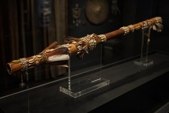 An ornate ceremonial blowpipe displayed in a museum case.