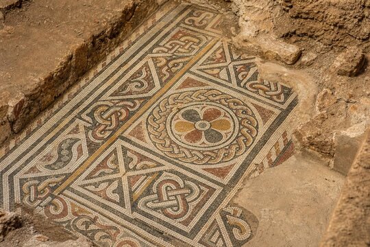 Close-up of ancient mosaic floor with geometric patterns, archaeological texture.