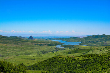 Fototapeta premium View of the mountain and the valley. The landscape of the lake with mountains in the background. Beautiful nature landscape with lake, green fields and mountains. River and mount
