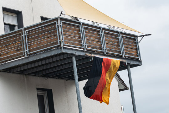Flag of Germany hanging from a balcony in an urban area