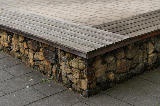 Wooden bench and stone wall in outdoor area near pavement