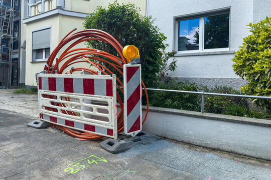 Construction site shows safety barrier and orange cables near building