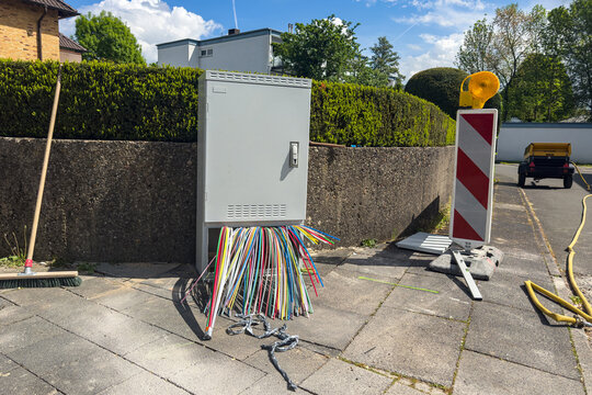 Workers set up cables near a utility box in a parking lot