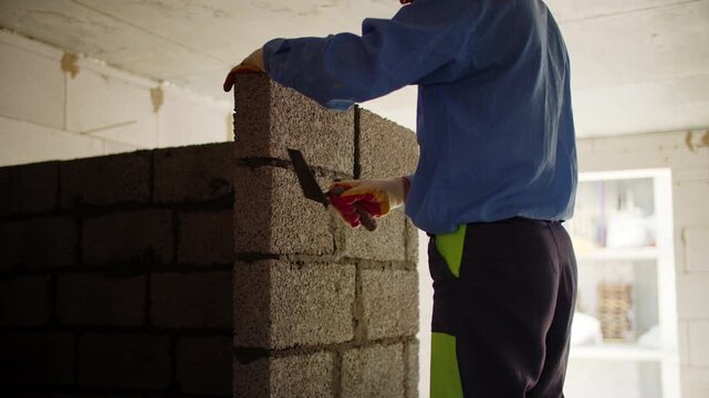 Builder adjusting concrete block wall inside unfinished building