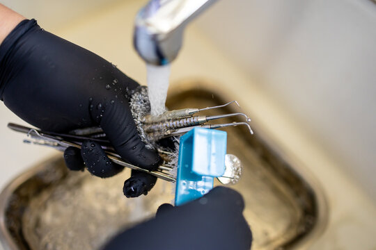 Dental Instruments Being Rinsed Under Running Water in Sink