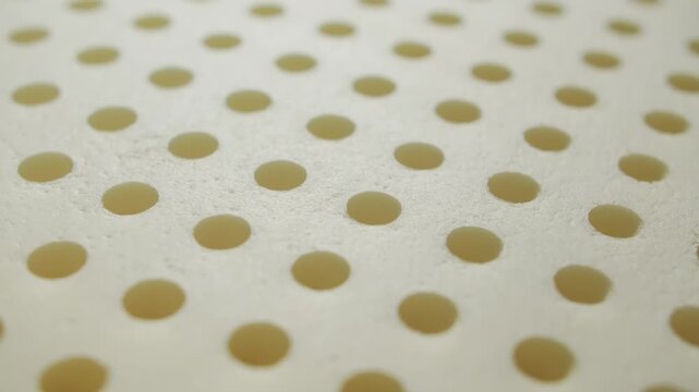 Close-up of a memory foam pillow layer with perforated surface. Soft breathable material with pressure-relief and shape-retaining properties.