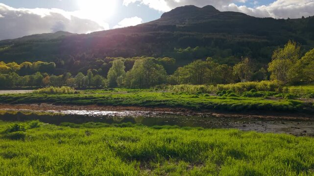 Low and slow drone flight over the lush green banks of Loin Water in Arrochar during a bright summer evening, with Ben Arthur towering in the background.