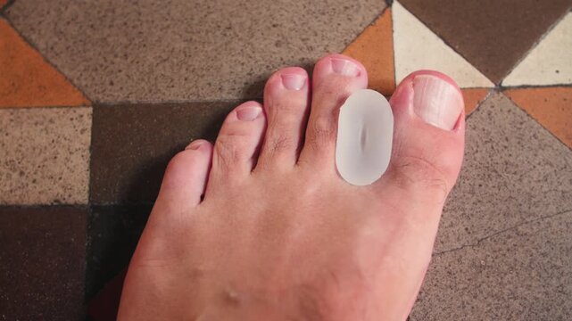 Close-up shot of a human foot with a silicone toe separator placed between the toes. The footage highlights foot care, hygiene, and wellness routines.