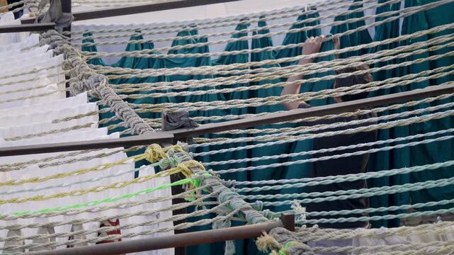 Daylight outdoor shot of an Indian Asian man or male worker or laundryman hanging clothes on the lines in the Dhobi Ghat, one of the largest an open air manual laundries in the world, in the downtown 