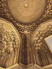 Naklejka premium Ornate golden dome interior with muqarnas vaulting at Shah-i-Zinda necropolis in Samarkand. Ideal for travel publications, cultural heritage features, and architectural studies.