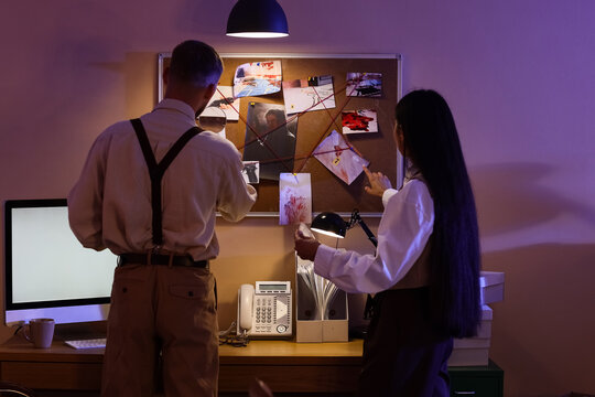 Detectives investigating crime scene evidence board with photos and red string in a dark office setting, the individuals are focused on analyzing the visual information to solve a complex case