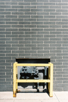 Yellow Guard Rail Protecting Gas Meter Against Brick Wall