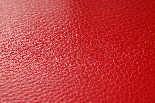 Vibrant red leather texture background with detailed grain pattern, close-up macro view of material surface for design and upholstery