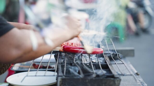 Filipino Vendor Grilling Hotdogs and Isaw at Street Market in the Philippines