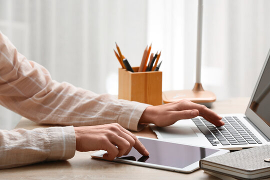 Young female programmer working with laptop and tablet in office, closeup