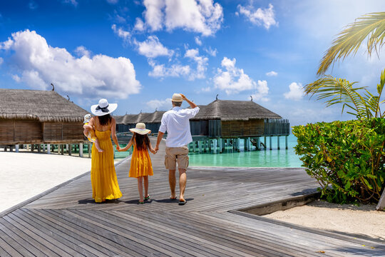 Rear view of a elegant family enjoying the tropical Maldives islands during their vacations in the Indian Ocean