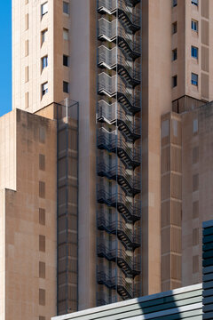 Apartment tower facade in Benidorm reveals stacked balconies and exterior stair detail, with highrise residential architecture rising in vertical light
