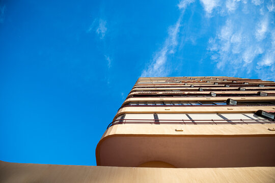 Apartment tower corner in Benidorm rises above curved wall and blue sky, with balconies, facade, highrise residential architecture and sunlit exterior
