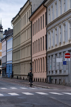 A pedestrian crosses a quiet street in Oslo, where crosswalk, facades, urban architecture, buildings and sidewalk shape the city view