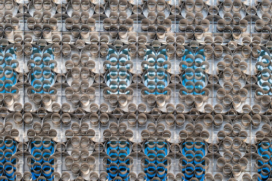 Circular facade modules repeat across modern architecture as blue windows and patterned exterior texture fill the frame with urban geometry