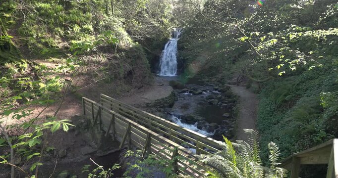 wooden bridge with the cascading Gleno waterfall in the background