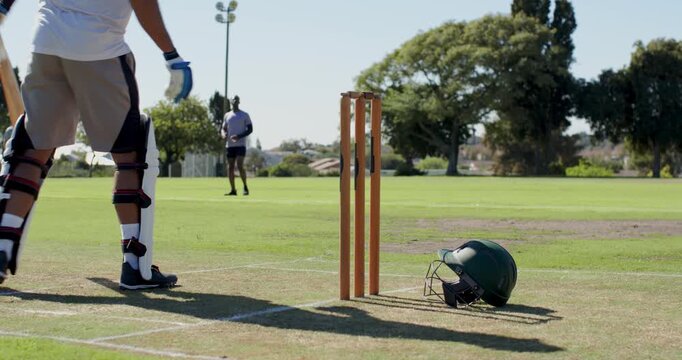 Reacting to bowler run-up, asian batsman adjusting stance grip facing ball on cricket pitch