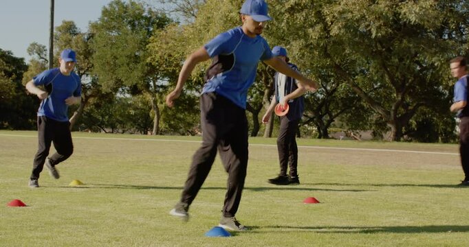 Male in blue sportswear running mid-stride in park sports field, with training cones