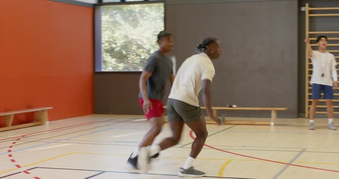 Coach signaling drill at gym african american player faking pass, dribbling ball