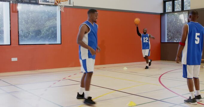 Scrambling for ball as pass bouncing african american teammates drilling at gym, celebrating
