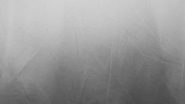 white fabric texture waving gently in soft cinematic lighting creating monochrome abstract shadows