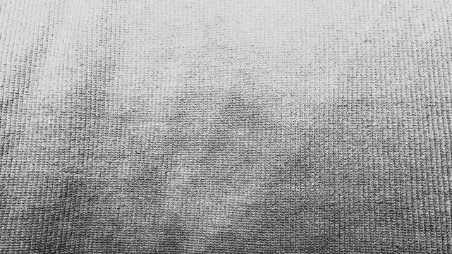 cinematic macro pan revealing monochrome grey knit textile texture as delicate shadow glides across cozy woven fabric